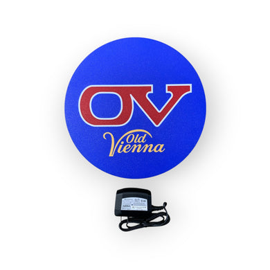 Blue circular sign with 'OV' and 'Old Vienna' text, accompanied by a power adapter on a white background.