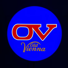 Load image into Gallery viewer, Logo of Old Vienna with red &#39;OV&#39; and yellow &#39;Vienna&#39; text on a blue circle against a black background on an indoor LED sign