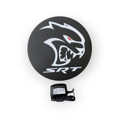 Round black SRT led sign with a power adapter on a white background