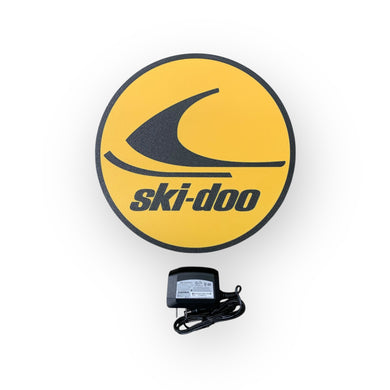 Ski-Doo led sign on a yellow background with a power adapter below.